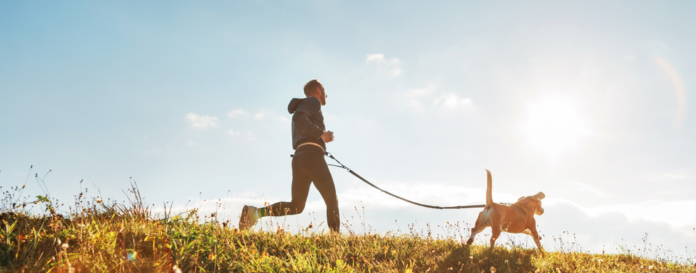 Dog owner jogging with his dog on a sunny day